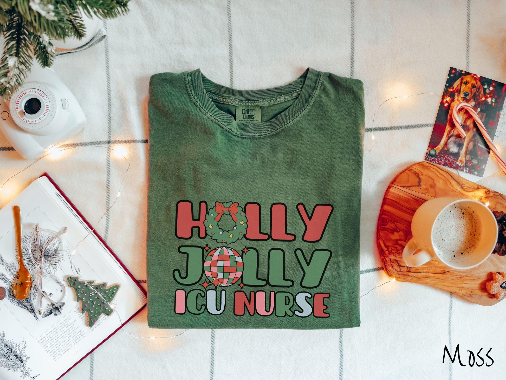 A cute, vintage moss colored Comfort Colors T-shirt with the text Holly Jolly ICU Nurse in red, green, pink, and blue font. The letter O in Holly is a Christmas wreath and the letter O in Jolly is a multi-colored disco ball.