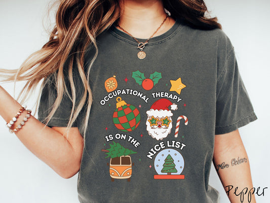 This vintage pepper colored Comfort Colors T-shirt features the text &#39;Occupational Therapy is on the nice list&#39; in white font, surrounded by Christmas lights, cranberries, Santa Claus, a candy cane, a snow globe, and other festive decorations.