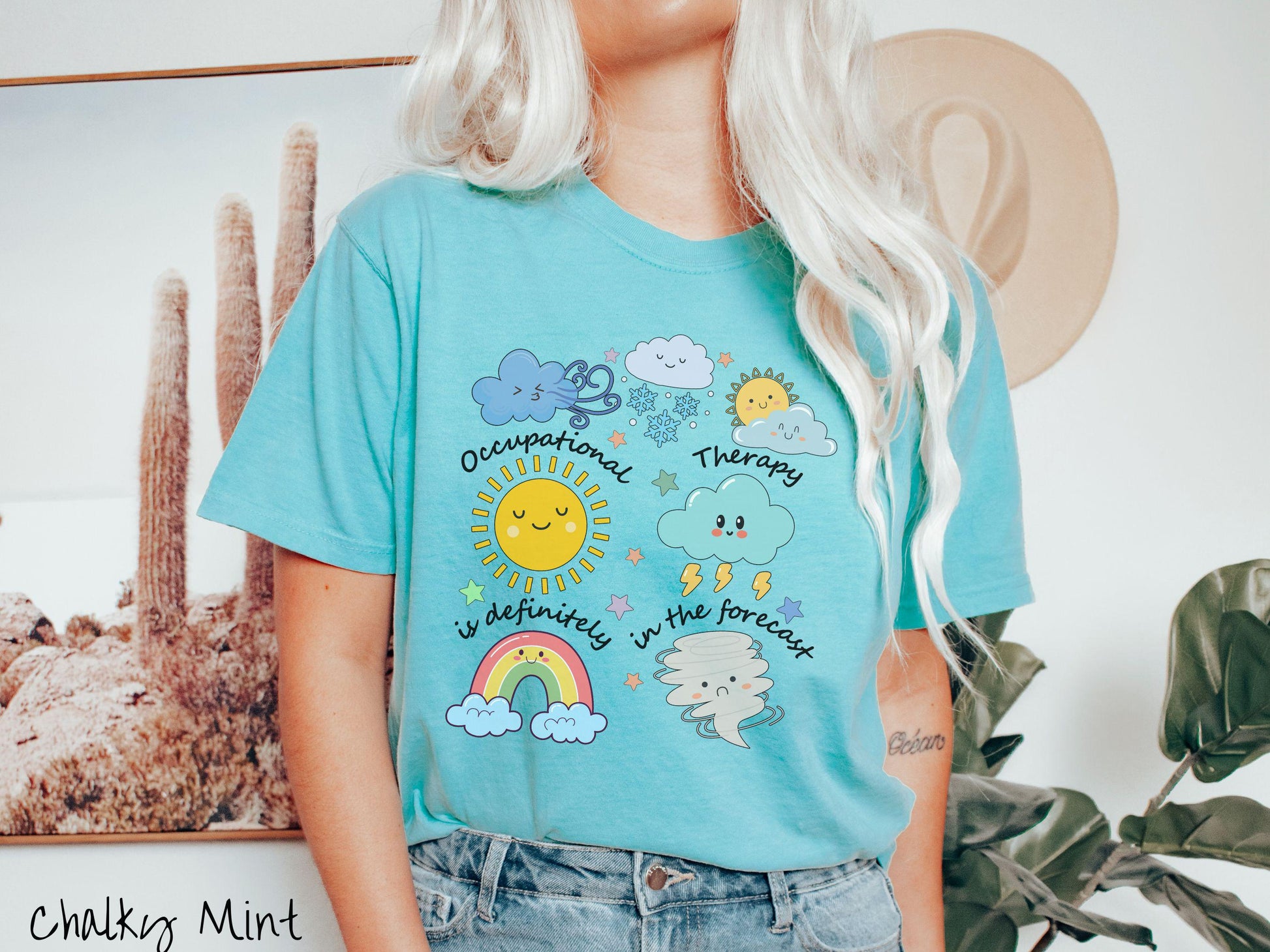 A vintage, chalky mint colored Comfort Colors T-shirt featuring the text Occupational Therapy is definitely in the forecast and surrounded by weather elements like clouds, rain clouds, a shining sun, lightning, a rainbow, and a tornado.