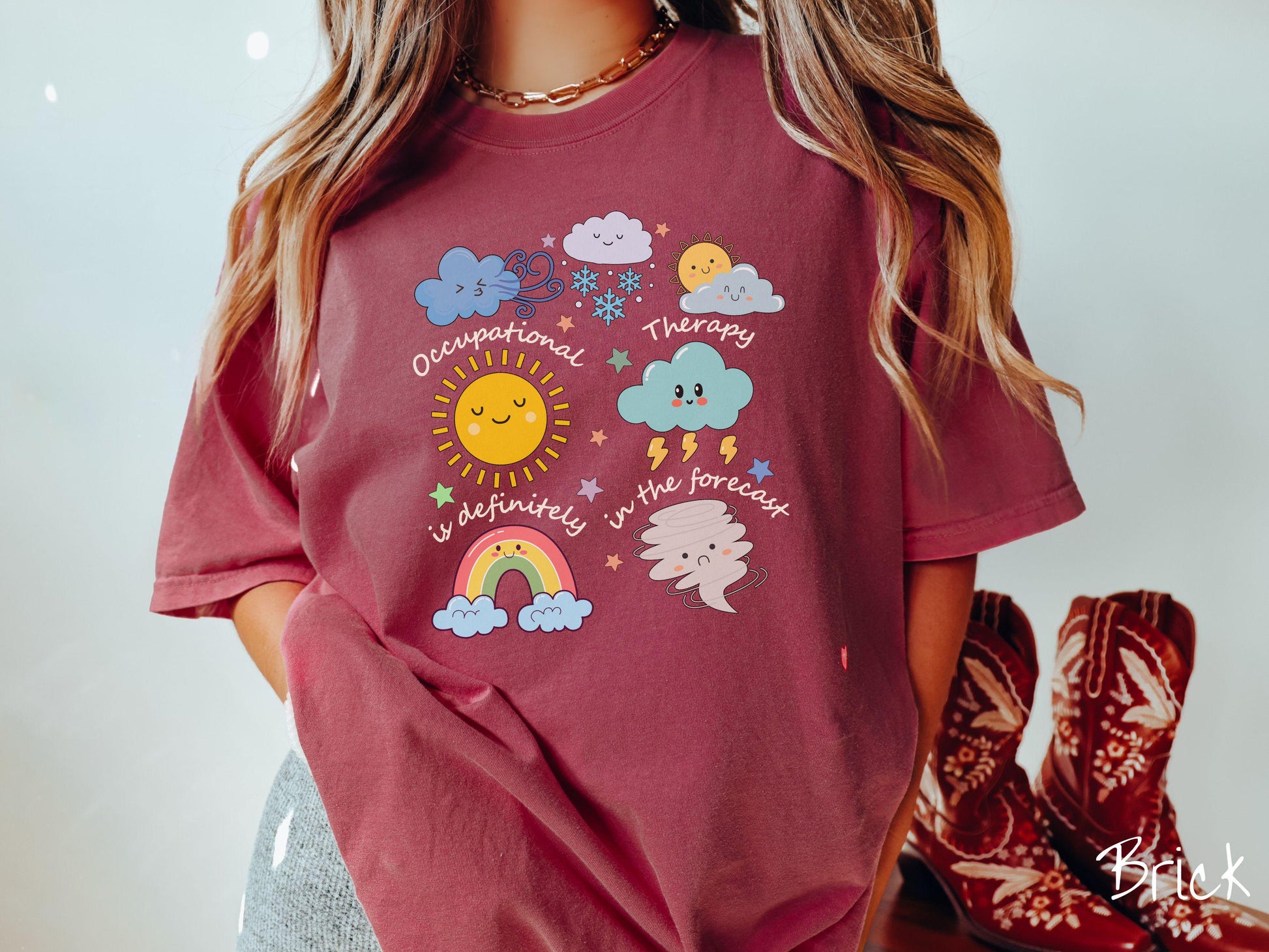 A vintage, brick colored Comfort Colors T-shirt featuring the text Occupational Therapy is definitely in the forecast and surrounded by weather elements like clouds, rain clouds, a shining sun, lightning, a rainbow, and a tornado.