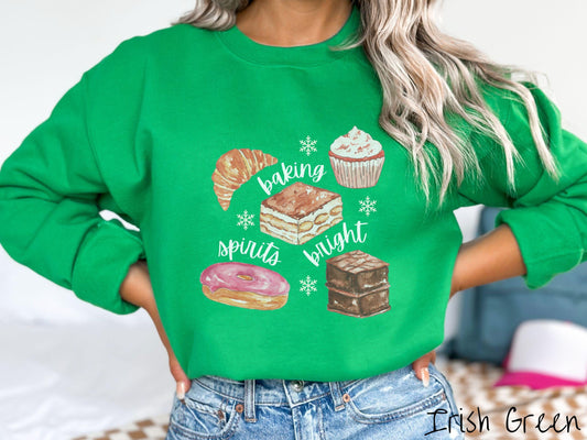 A vintage Irish green colored Gildan sweatshirt features the text &#39;baking spirits bright&#39; in white cursive font, accompanied by cute dessert illustrations and white snowflakes.