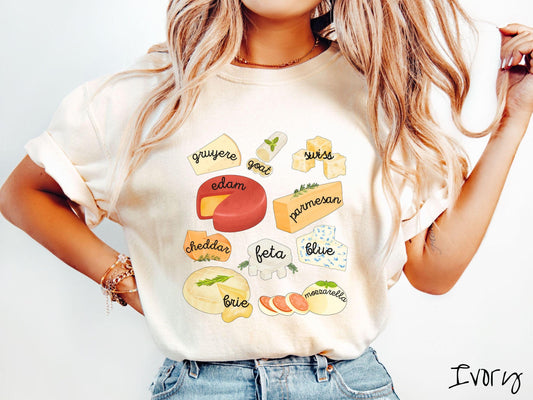 A vintage ivory colored T-shirt is perfect for cheese lovers with a grid pattern of various cheeses like feta, parmesan, gruyere, goat, swiss, edam, cheddar, blue, brie, and mozzarella listed.