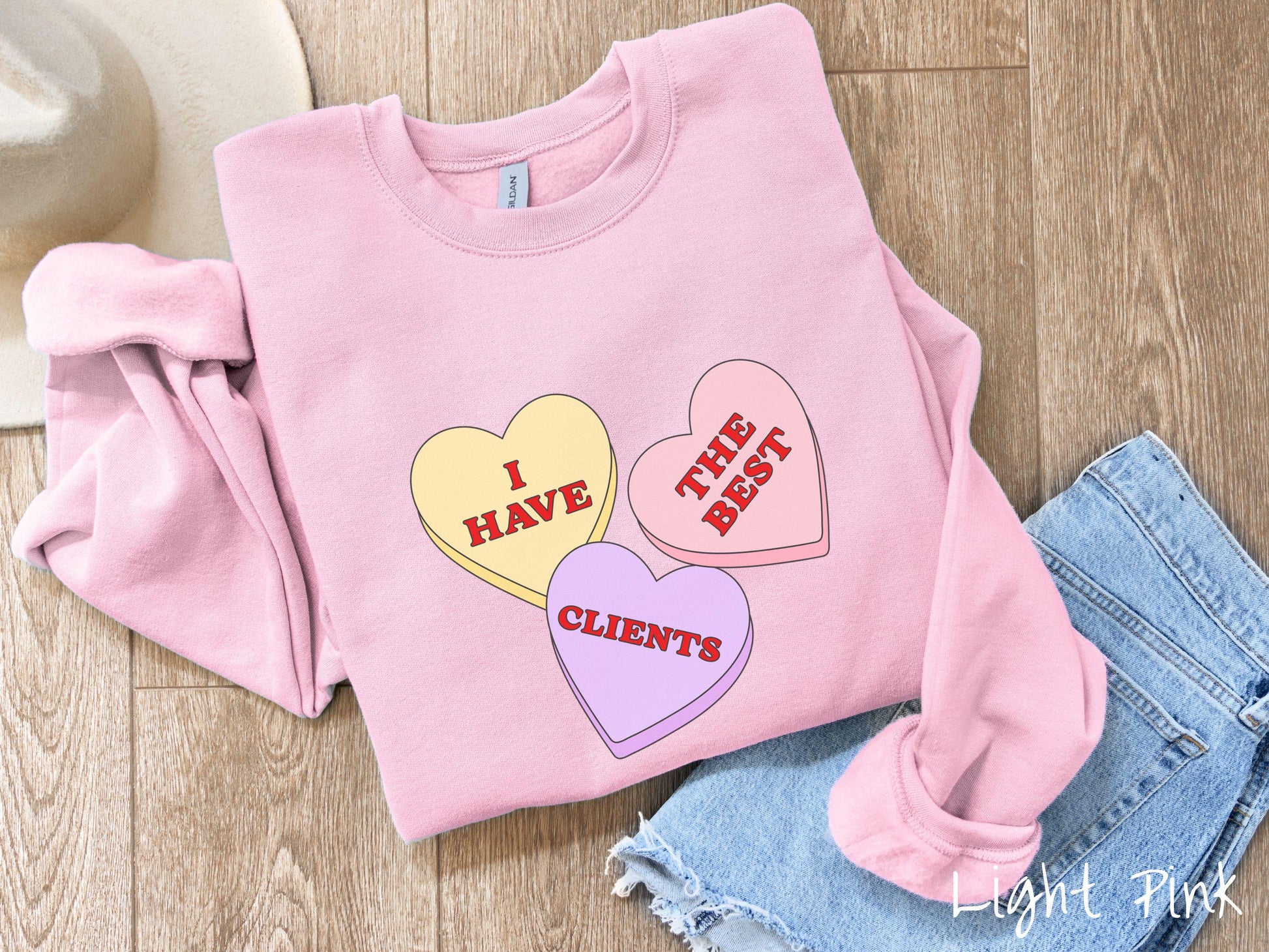 Show your appreciation for your amazing clients with this charming Gildan sweatshirt featuring three vibrant conversation hearts in yellow, red, and purple colors showcasing the text “I have the best clients” spread across the hearts.