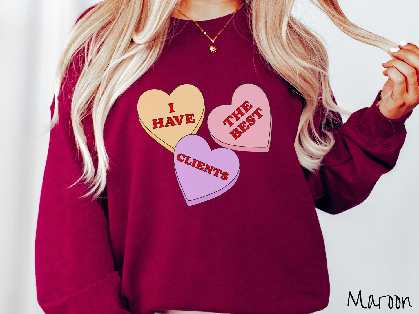 Show your appreciation for your amazing clients with this charming Gildan sweatshirt featuring three vibrant conversation hearts in yellow, red, and purple colors showcasing the text “I have the best clients” spread across the hearts.