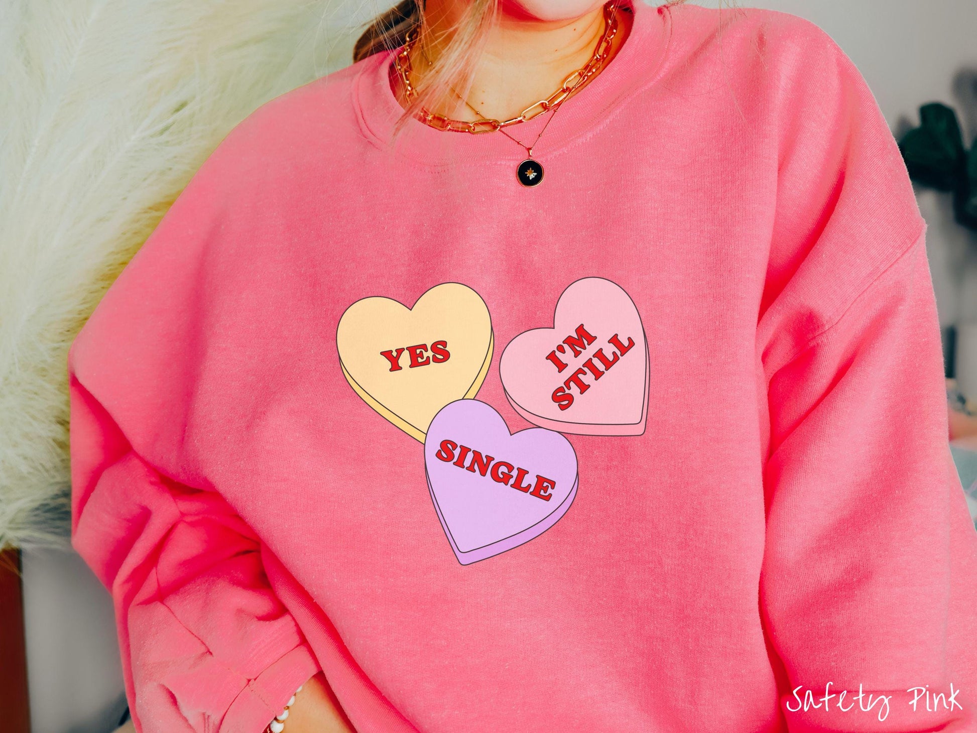 Make a bold statement this Valentine’s Day with this vintage Gildan sweatshirt featuring three vibrant conversation hearts in yellow, red, and purple, the design showcasing the cheeky phrase “Yes, I’m Still Single” spread across the hearts.