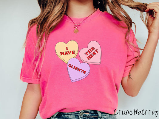 Show your appreciation for your amazing clients with this charming Comfort Colors t-shirt featuring three vibrant conversation hearts in yellow, red, and purple colors showcasing the text “I have the best clients” spread across the hearts.