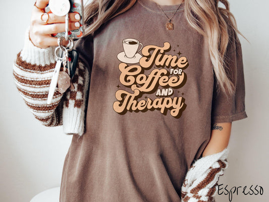 A vintage, espresso colored Comfort Colors t-shirt featuring the text Time for Coffee and Therapy with a cup of coffee and stars in the background, giving off a cozy and comforting vibe.