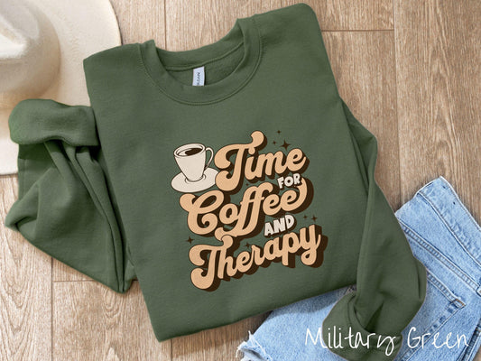 A vintage, military green colored Gildan sweatshirt featuring the text Time for Coffee and Therapy with a cup of coffee and stars in the background, giving off a cozy and comforting vibe.