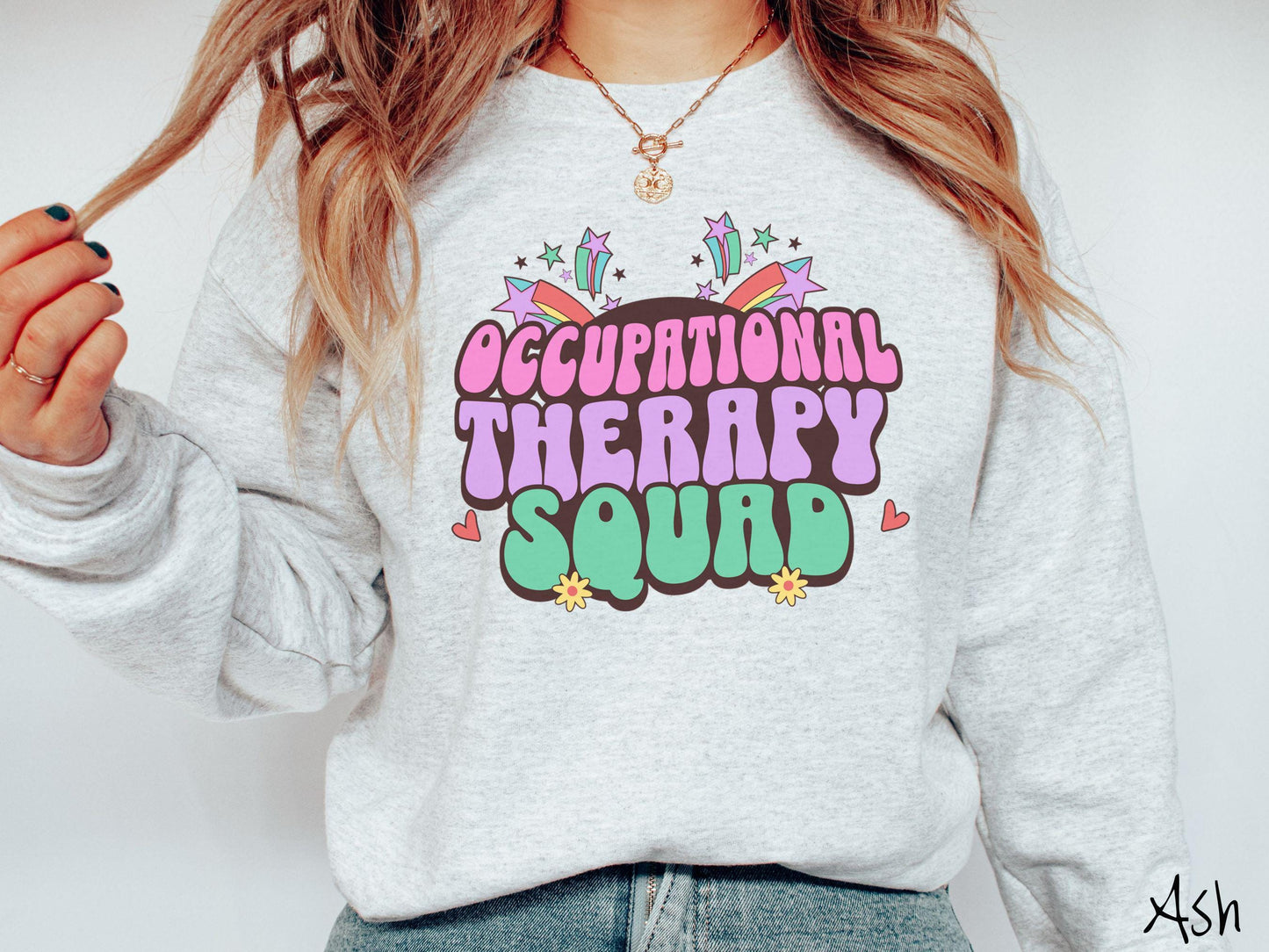 A vintage, ash colored Gildan sweatshirt with the text Occupational Therapy Squad in colorful font with red hearts, sunflowers, and shooting stars mixed in.