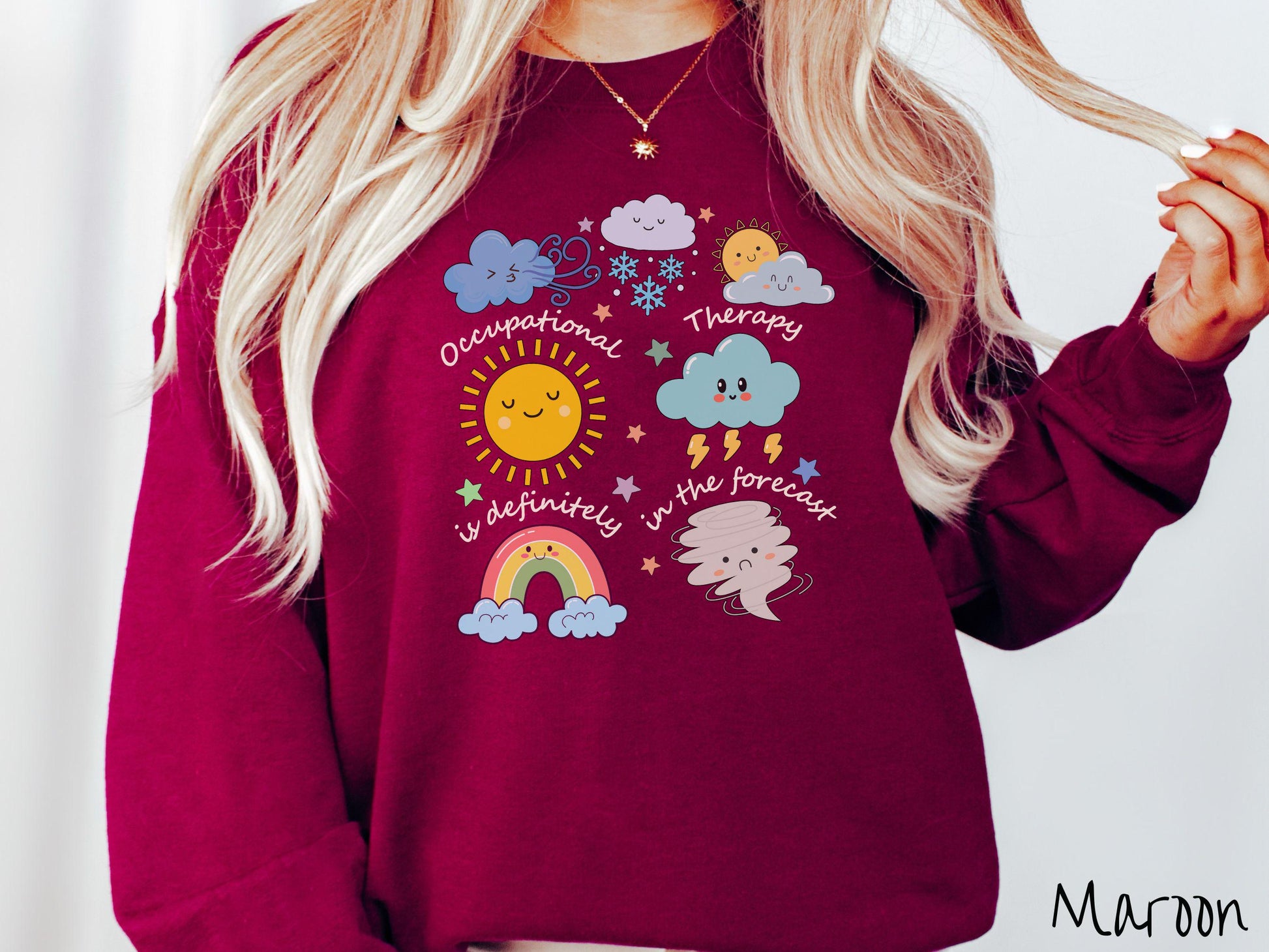 A vintage, maroon colored Gildan sweatshirt featuring the text Occupational Therapy is definitely in the forecast and surrounded by weather elements like clouds, rain clouds, a shining sun, lightning, a rainbow, and a tornado.