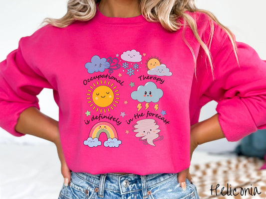 A vintage, heliconia colored Gildan sweatshirt featuring the text Occupational Therapy is definitely in the forecast and surrounded by weather elements like clouds, rain clouds, a shining sun, lightning, a rainbow, and a tornado.