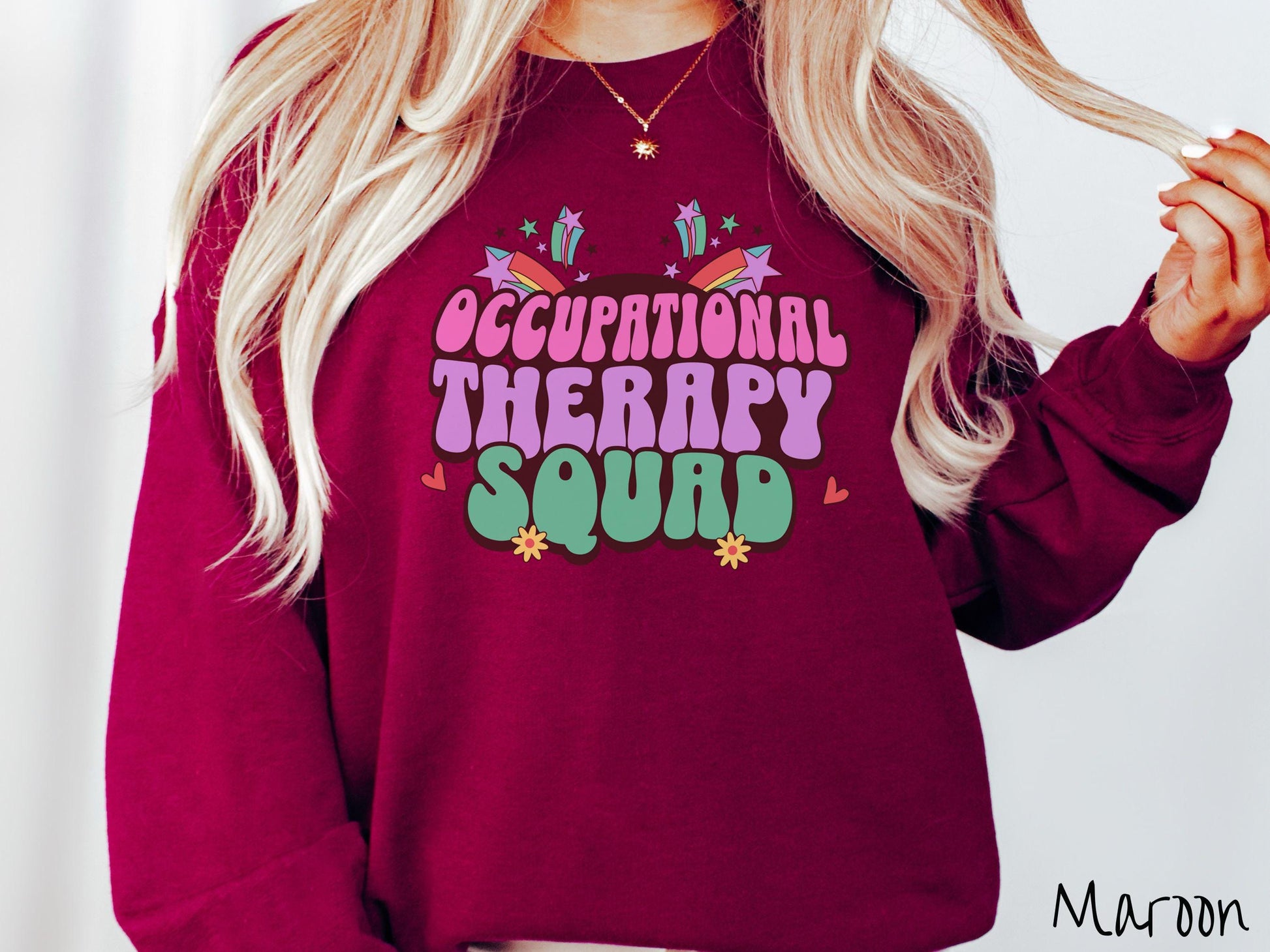 A vintage, maroon colored Gildan sweatshirt with the text Occupational Therapy Squad in colorful font with red hearts, sunflowers, and shooting stars mixed in.