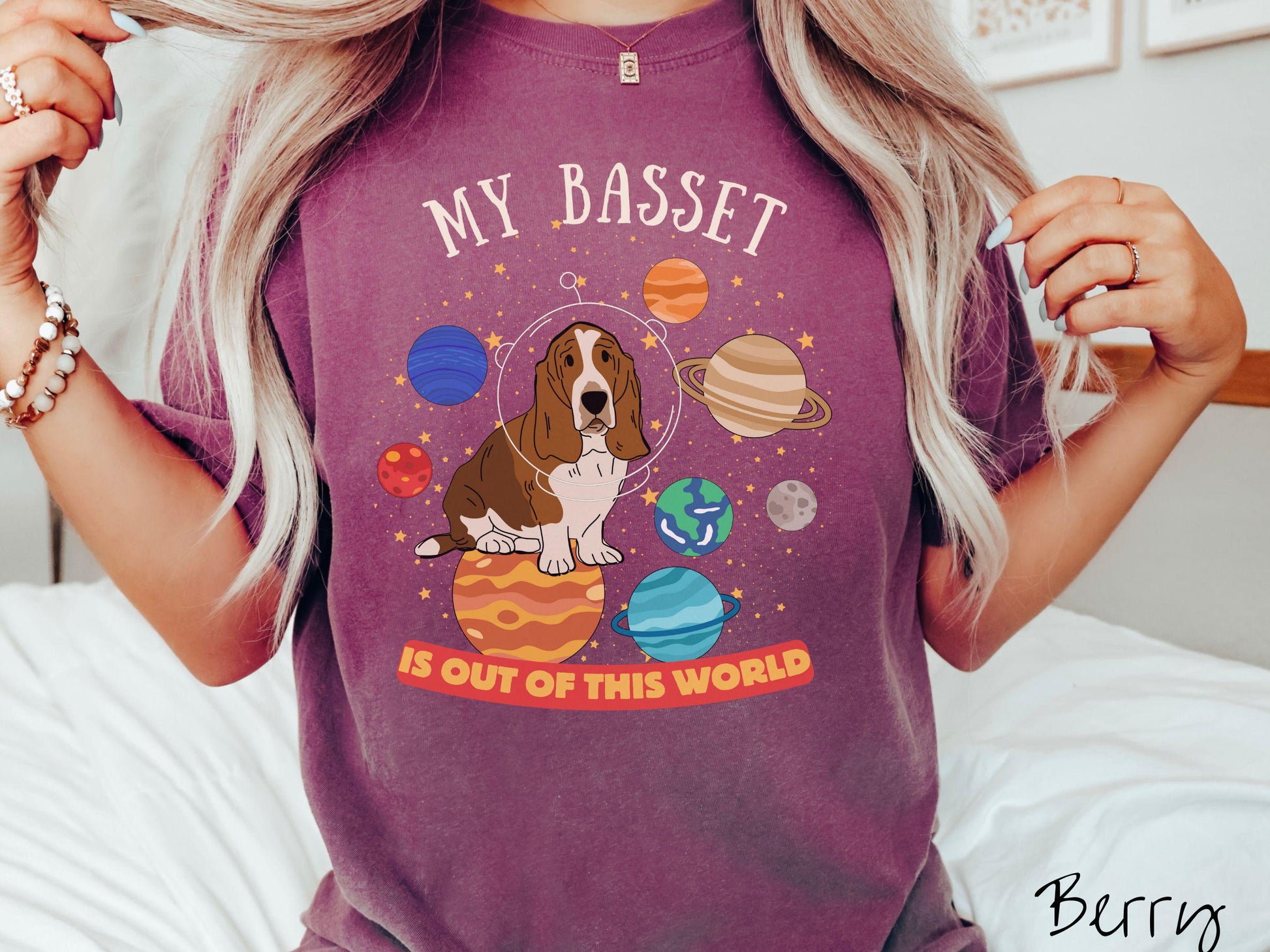 A vintage Comfort Colors t-shirt featuring the playful text &#39;My Basset is Out of This World&#39;. The design showcases a basset hound sitting proudly atop Jupiter, surrounded by a vibrant solar system filled with colorful planets and twinkling stars.