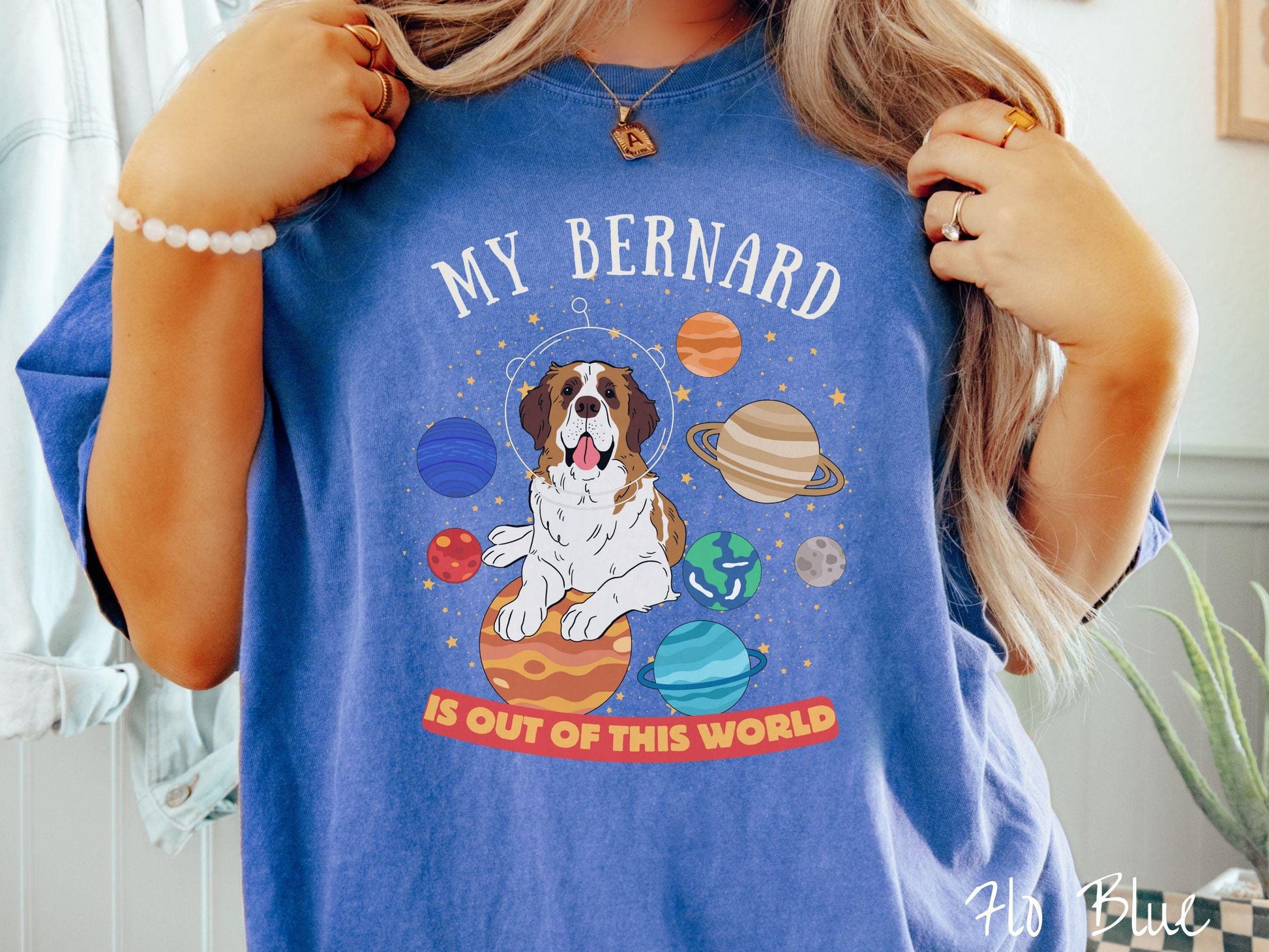 A vintage Comfort Colors t-shirt featuring the text &#39;My Bernard is Out of This World&#39;. The design showcases an adorable St. Bernard sitting proudly atop Jupiter, surrounded by a vibrant solar system filled with colorful planets and twinkling stars.