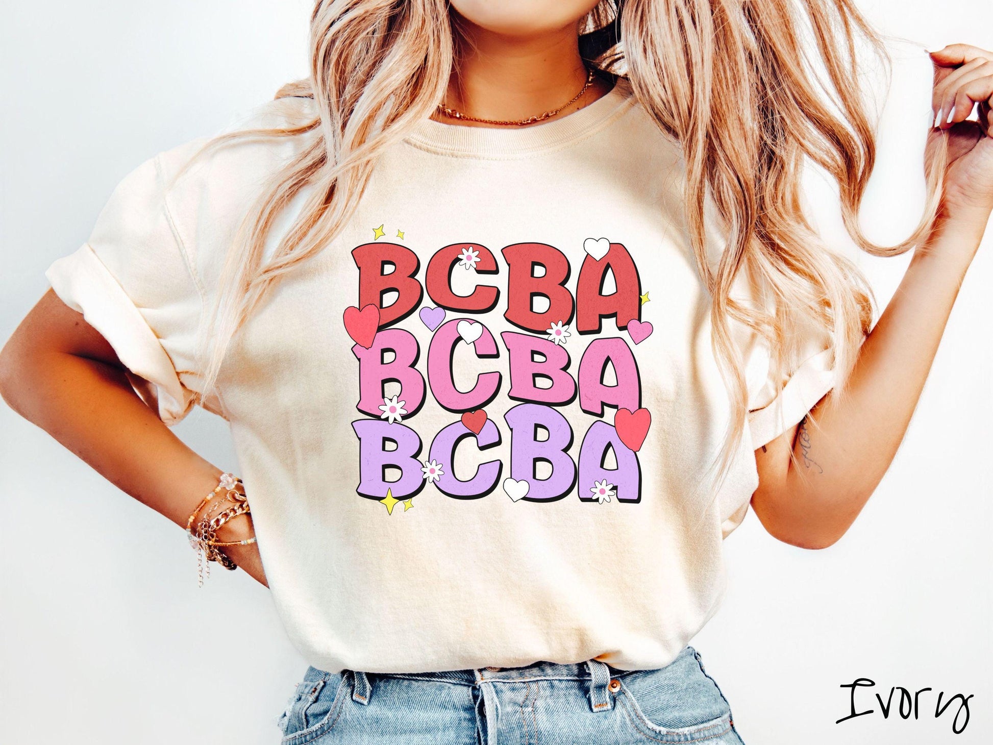 A vibrant Comfort Colors T-shirt with the text BCBA written three times vertically, accompanied by tiny hearts, stars, and flowers. Perfect for Board Certified Behavior Analysts, this tee is a great Valentine&#39;s Day gift to show appreciation and love.