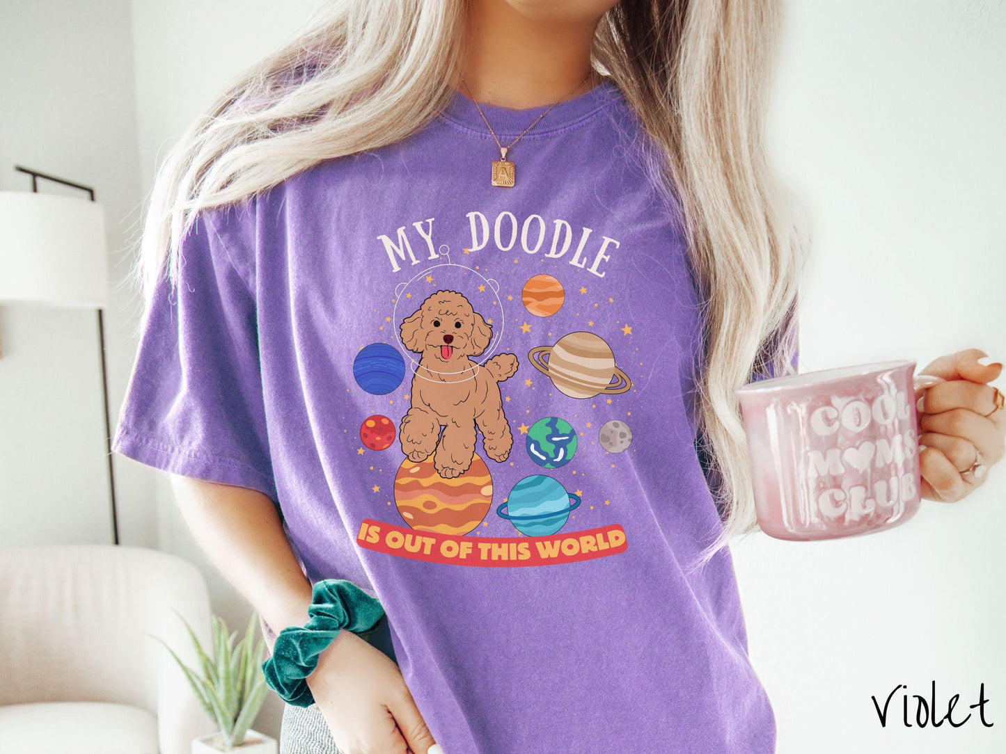 A vintage Comfort Colors t-shirt featuring the text My Doodle is Out of This World. The design showcases a Doodle sitting proudly atop Jupiter, surrounded by a vibrant solar system filled with colorful planets and twinkling stars.