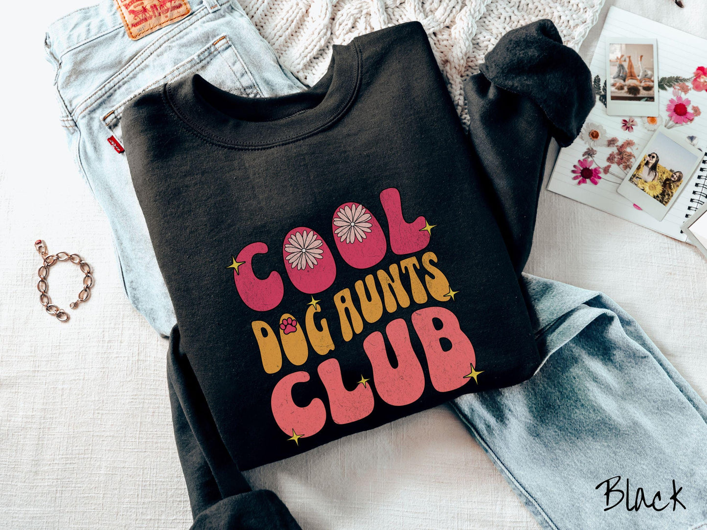 A vintage Gildan sweatshirt featuring the text "Cool Dog Aunts Club" in bold red, yellow, and orange fonts with flower petals nestled in the "O" of COOL, a cute red paw print in the "O" of DOG, and sparkling yellow stars throughout.