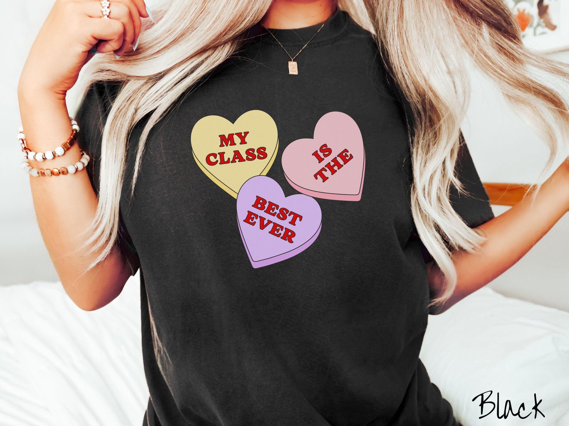 A charming vintage-style Valentine’s Day Comfort Colors t-shirt featuring three vibrant conversation hearts in yellow, red, and purple, this design displays the text “My class is the best ever” spread across the hearts.