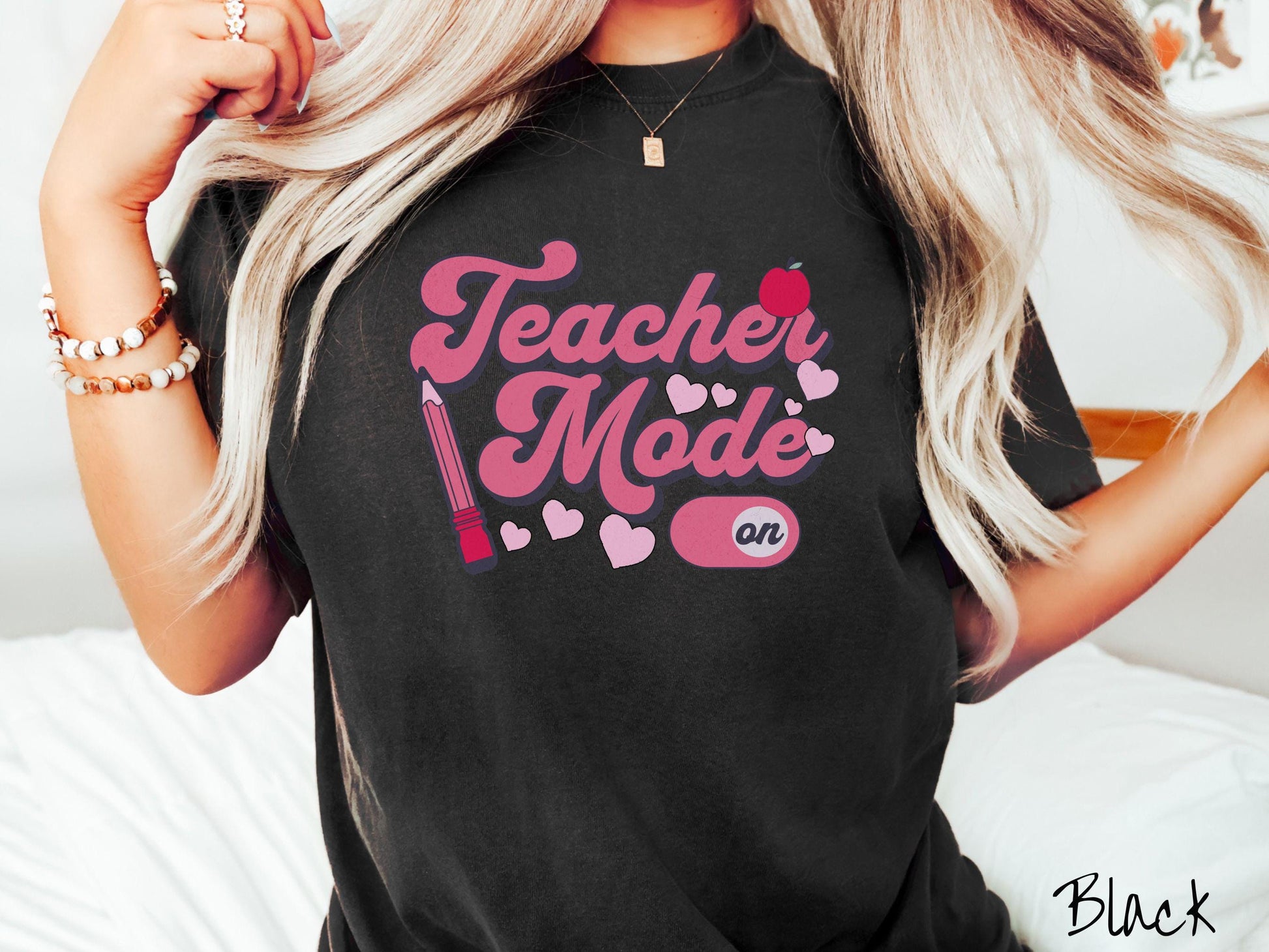 A vintage Comfort Colors t-shirt featuring the phrase “Teacher Mode” in playful pink font, an “On” button toggled to the “On” position, and with charming details like a red pencil, a red apple, and pink hearts sprinkled throughout.