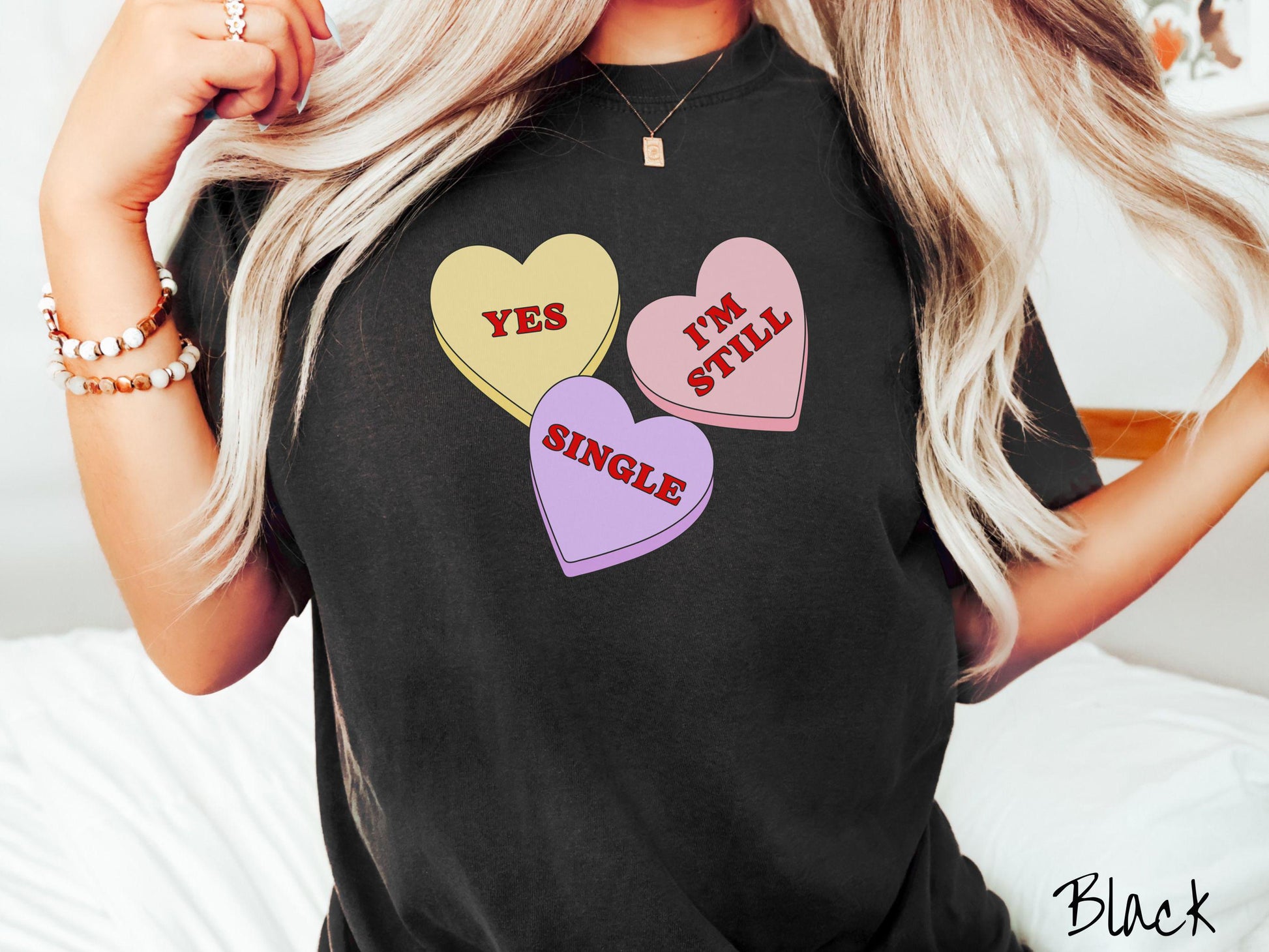 Make a bold statement this Valentine’s Day with this vintage Comfort Colors t-shirt featuring three vibrant conversation hearts in yellow, red, and purple, the design showcasing the cheeky phrase “Yes, I’m Still Single” spread across the hearts.