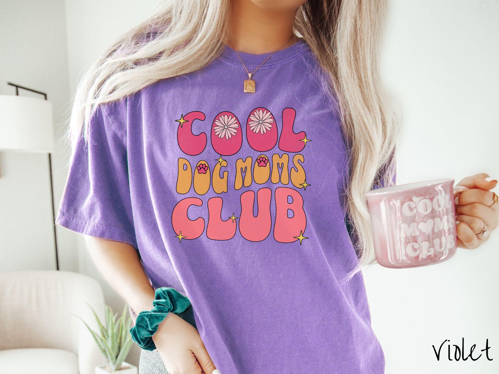 A vintage Comfort Colors t-shirt featuring the playful text Cool Dog Moms Club, this design is full of charming details. From flower petals nestled in the &quot;O&quot; of COOL to a cute red paw print in the &quot;O&quot; of DOG and sparkling yellow stars throughout.