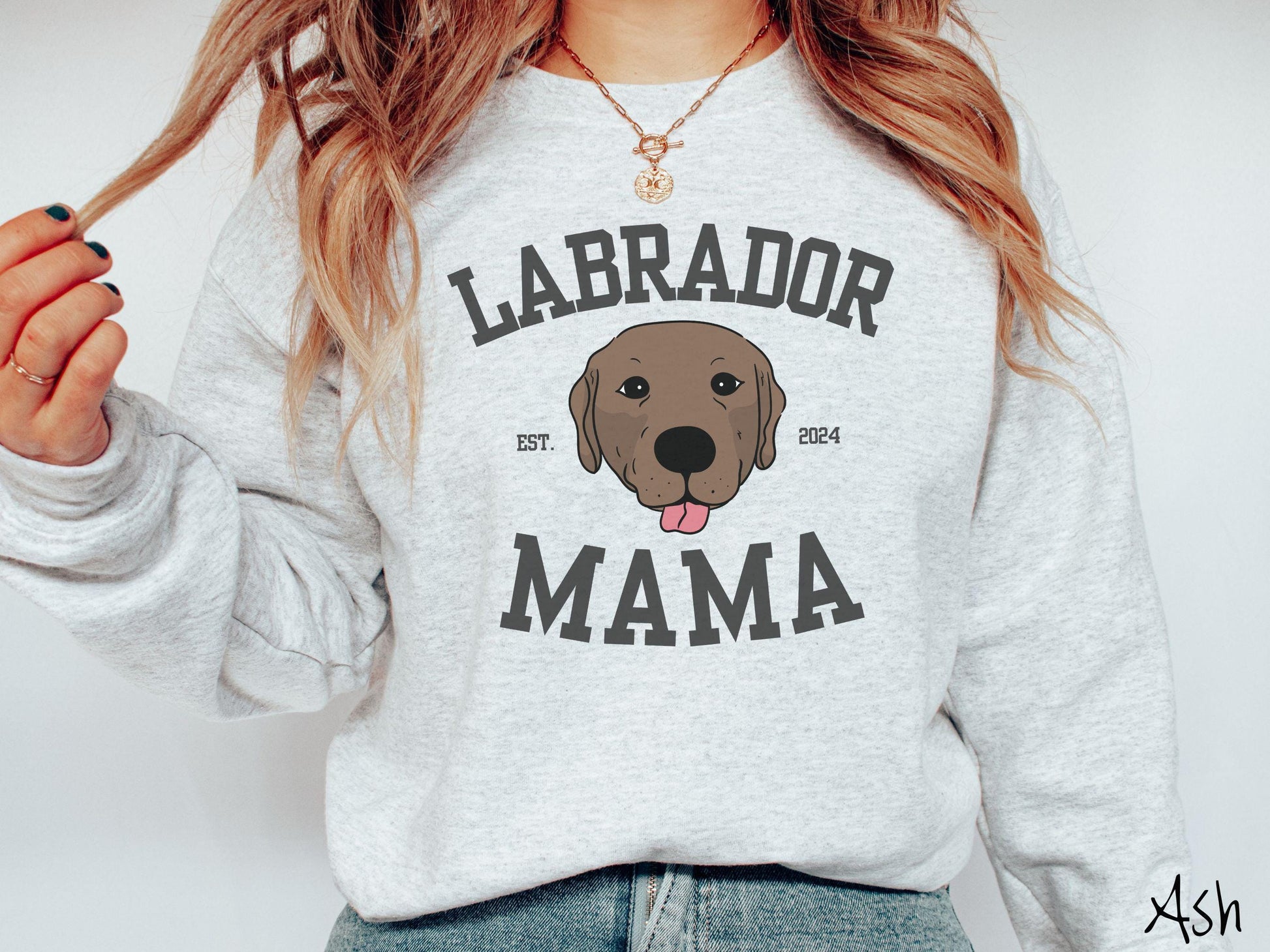A vintage Gildan sweatshirt featuring bold block lettering that reads &#39;Labrador Mama.&#39; At the center of the design, a playful chocolate Labrador with its tongue out steals the spotlight, framed by the stylish text &#39;EST. 2024.&#39;
