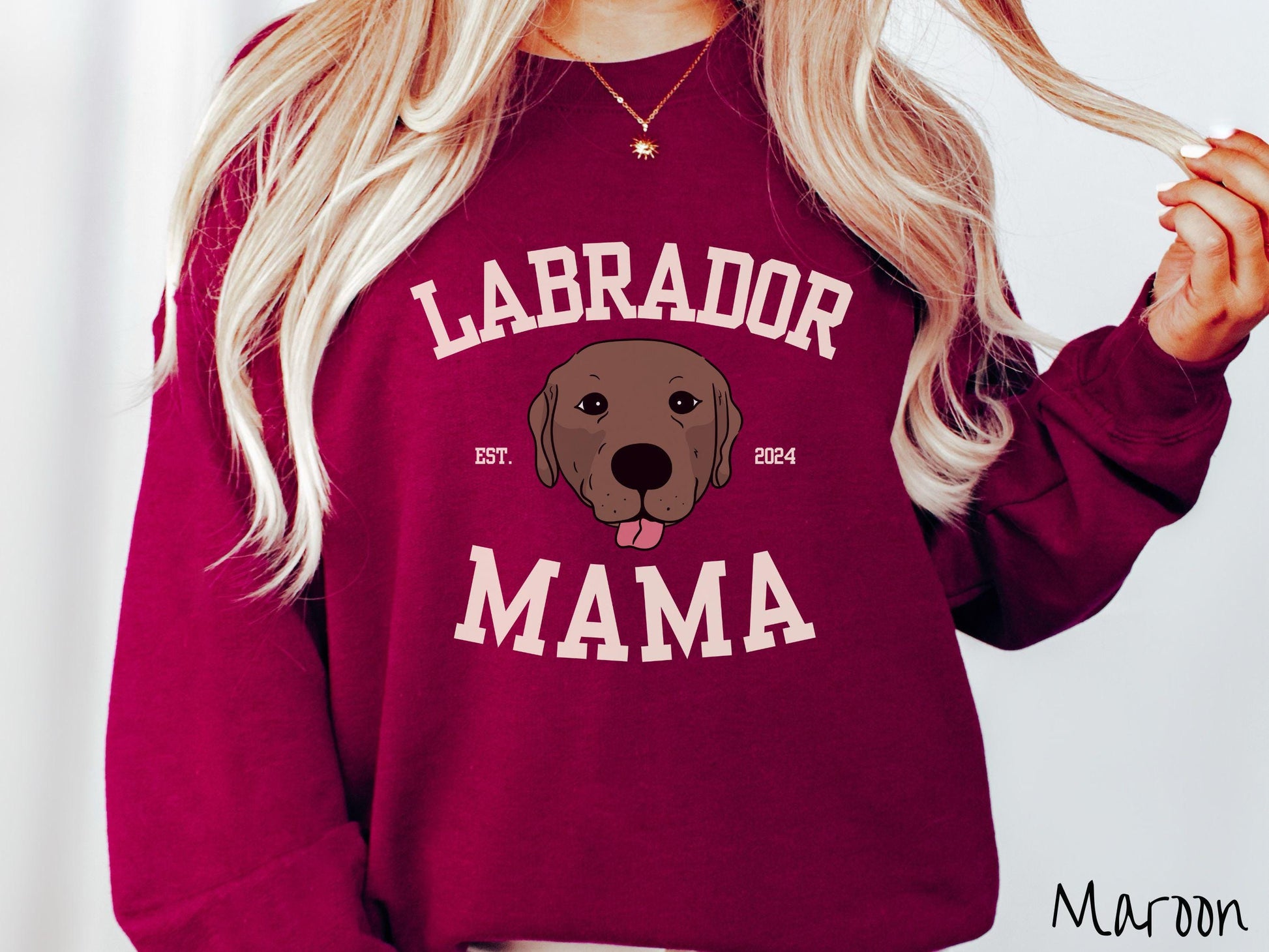 A vintage Gildan sweatshirt featuring bold block lettering that reads &#39;Labrador Mama.&#39; At the center of the design, a playful chocolate Labrador with its tongue out steals the spotlight, framed by the stylish text &#39;EST. 2024.&#39;