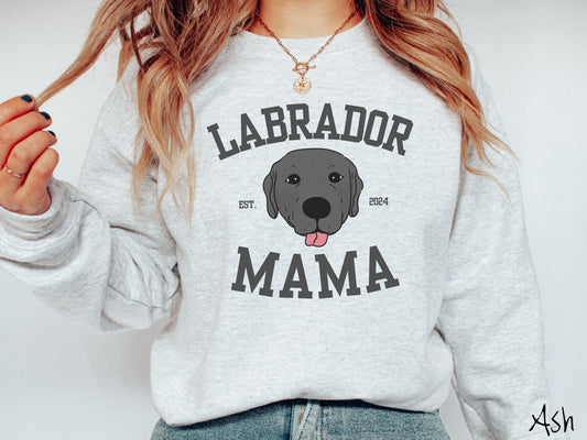 A vintage Gildan sweatshirt featuring bold block lettering that reads &#39;Labrador Mama.&#39; At the center of the design, a playful black Labrador with its tongue out steals the spotlight, framed by the stylish text &#39;EST. 2024.&#39;