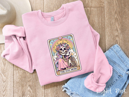 A vintage Gildan sweatshirt features a tarot card design with the text “The Dog Mom” along the bottom, framed by red hearts. Inside the tarot card is a female skeleton with flowing hair adorned with colorful flowers holding a skeleton dog.