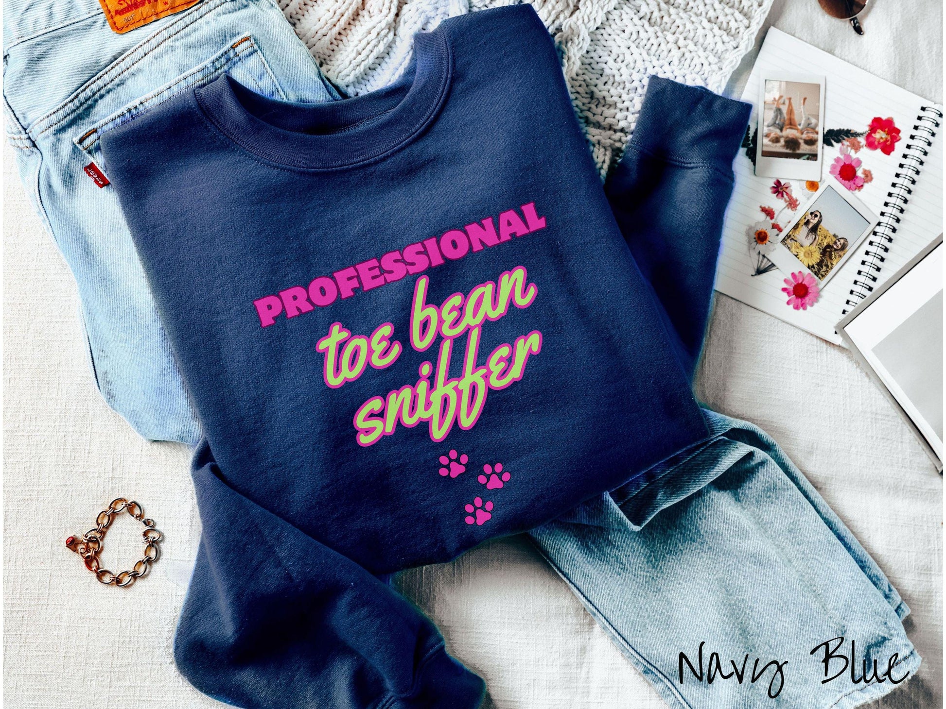 A vintage Gildan sweatshirt perfect for dog lovers who can’t resist those adorable toe beans! It features the funny text Professional Toe Bean Sniffer in bold pink and green fluorescent font, and below the text are three pink dog paw prints.