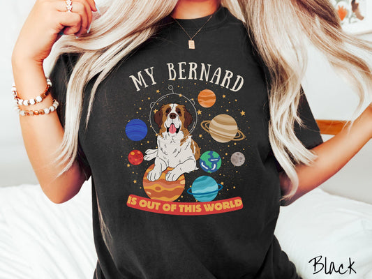 A vintage Comfort Colors t-shirt featuring the text &#39;My Bernard is Out of This World&#39;. The design showcases an adorable St. Bernard sitting proudly atop Jupiter, surrounded by a vibrant solar system filled with colorful planets and twinkling stars.