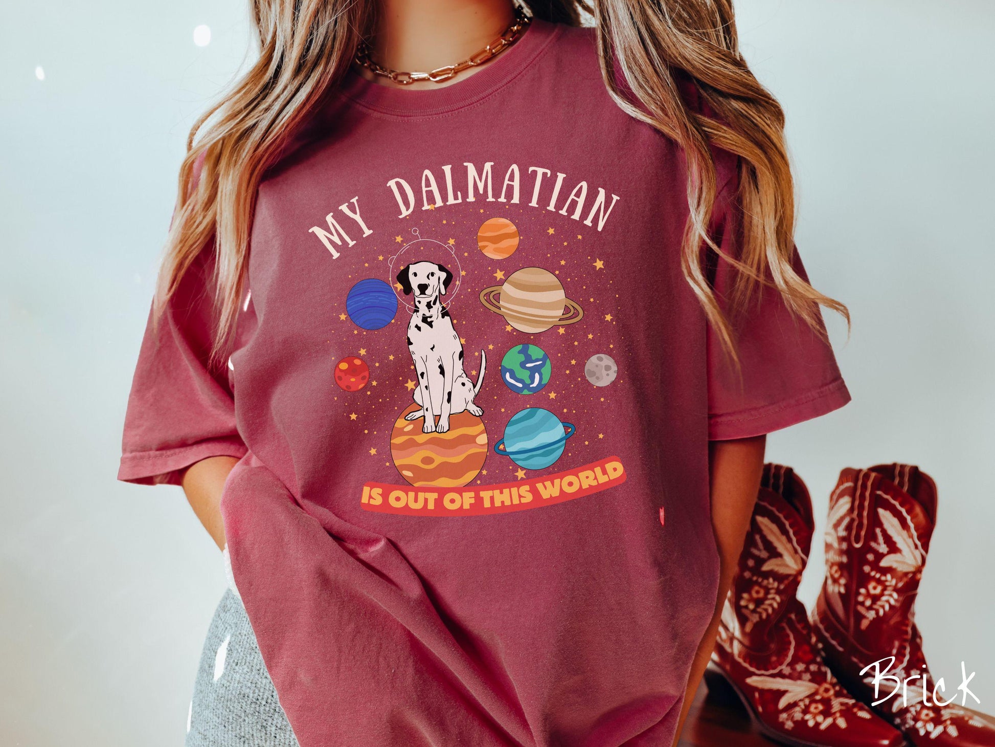A vintage Comfort Colors t-shirt featuring the text My Dalmation is Out of This World. The design showcases a Dalmation sitting proudly atop Jupiter, surrounded by a vibrant solar system filled with colorful planets and twinkling stars.