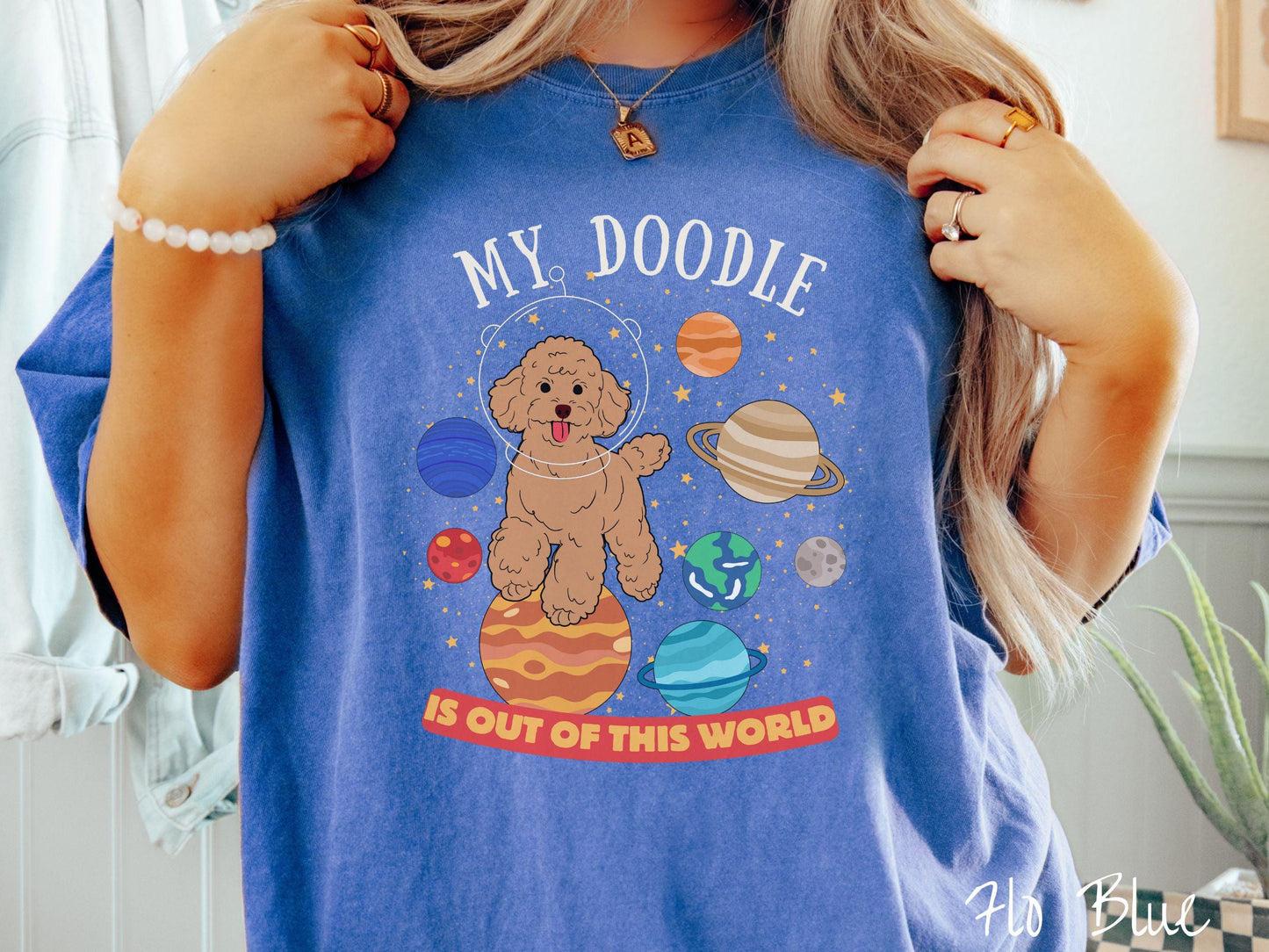 A vintage Comfort Colors t-shirt featuring the text My Doodle is Out of This World. The design showcases a Doodle sitting proudly atop Jupiter, surrounded by a vibrant solar system filled with colorful planets and twinkling stars.