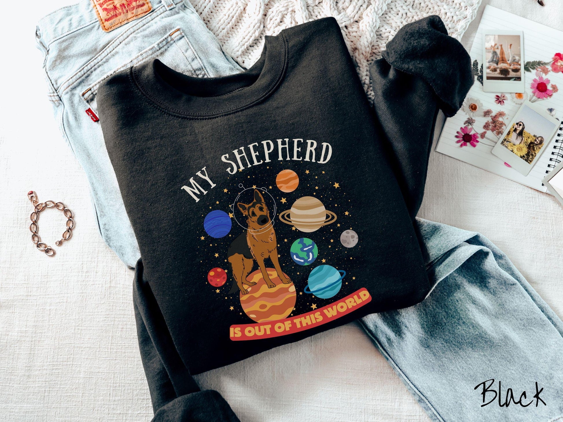 A vintage Gildan sweatshirt featuring the text My Shepherd is Out of This World. The design showcases a German Shepherd sitting proudly atop Jupiter, surrounded by a vibrant solar system filled with colorful planets and twinkling stars.