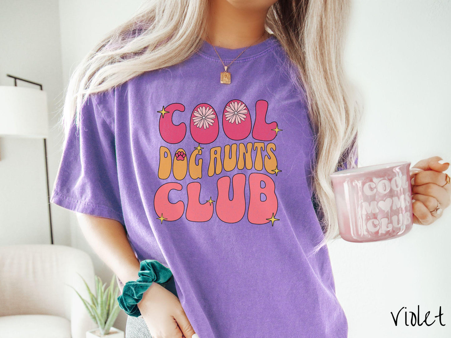 A vintage Comfort Colors t-shirt featuring the text "Cool Dog Aunts Club" in bold red, yellow, and orange fonts with flower petals nestled in the "O" of COOL, a cute red paw print in the "O" of DOG, and sparkling yellow stars throughout.