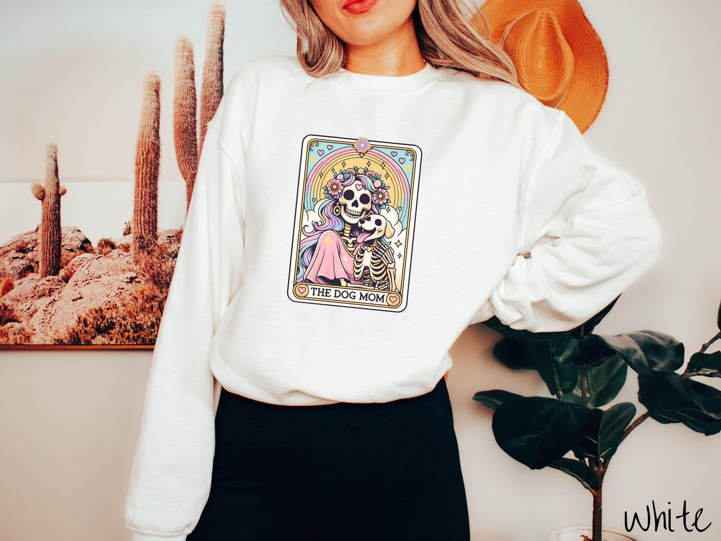 A vintage Gildan sweatshirt features a tarot card design with the text “The Dog Mom” along the bottom, framed by red hearts. Inside the tarot card is a female skeleton with flowing hair adorned with colorful flowers holding a skeleton dog.
