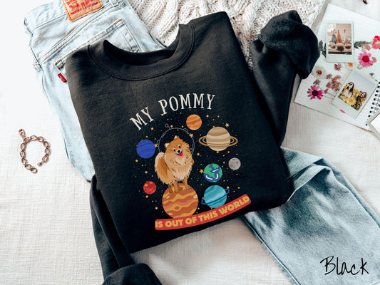 A vintage Gildan sweatshirt featuring the text My Pomeranian is Out of This World. The design showcases a German Shepherd sitting proudly atop Jupiter, surrounded by a vibrant solar system filled with colorful planets and twinkling stars.