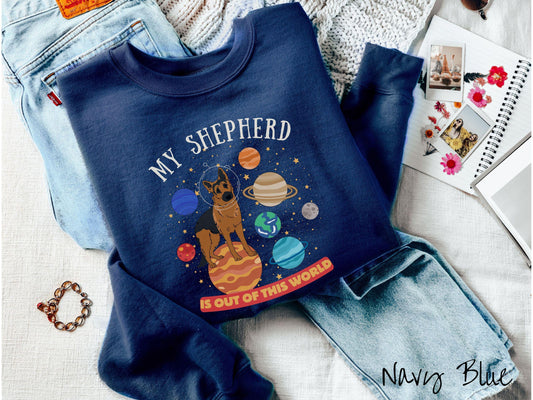 A vintage Gildan sweatshirt featuring the text My Shepherd is Out of This World. The design showcases a German Shepherd sitting proudly atop Jupiter, surrounded by a vibrant solar system filled with colorful planets and twinkling stars.